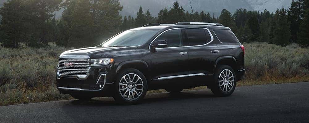 Black SUV parked on a scenic road with trees and mountains in the background.