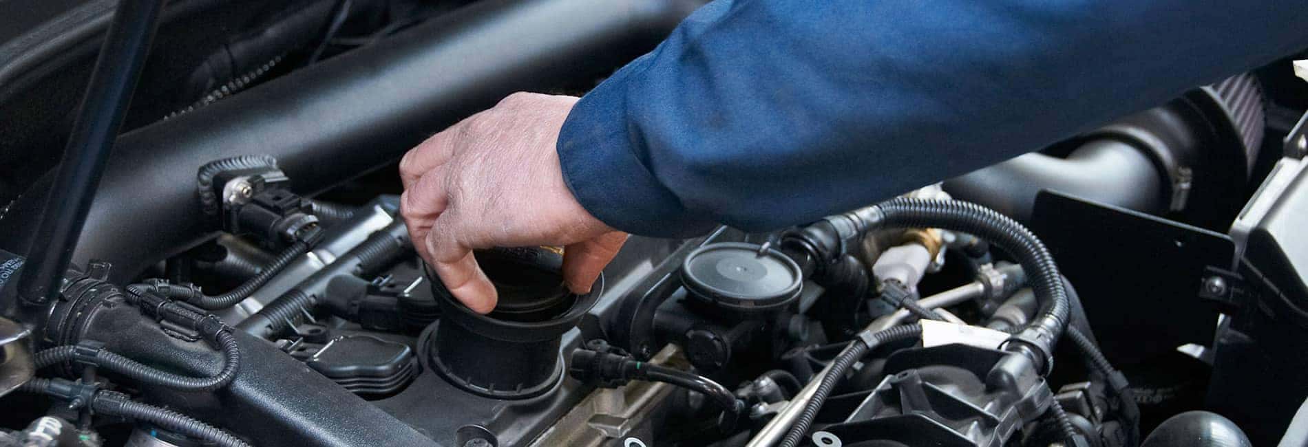 A mechanic's hand performing engine maintenance, adjusting a component under the hood.