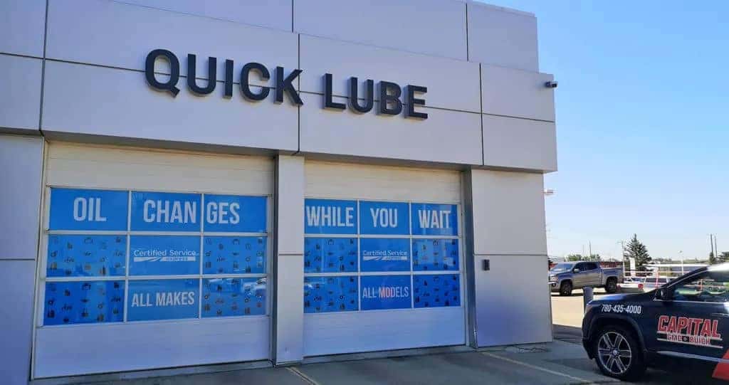 Quick Lube service center with signage for oil changes while you wait. A branded vehicle is parked outside.