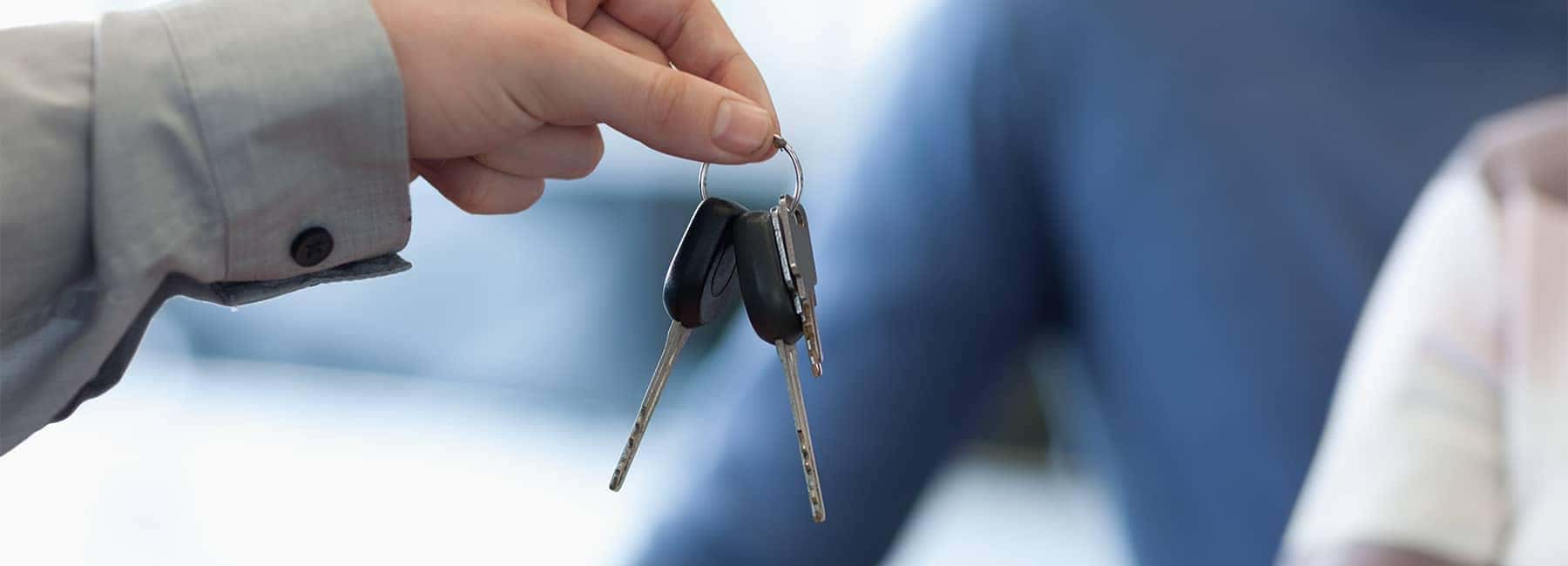 Hand holding car keys, symbolizing vehicle transaction or car rental.