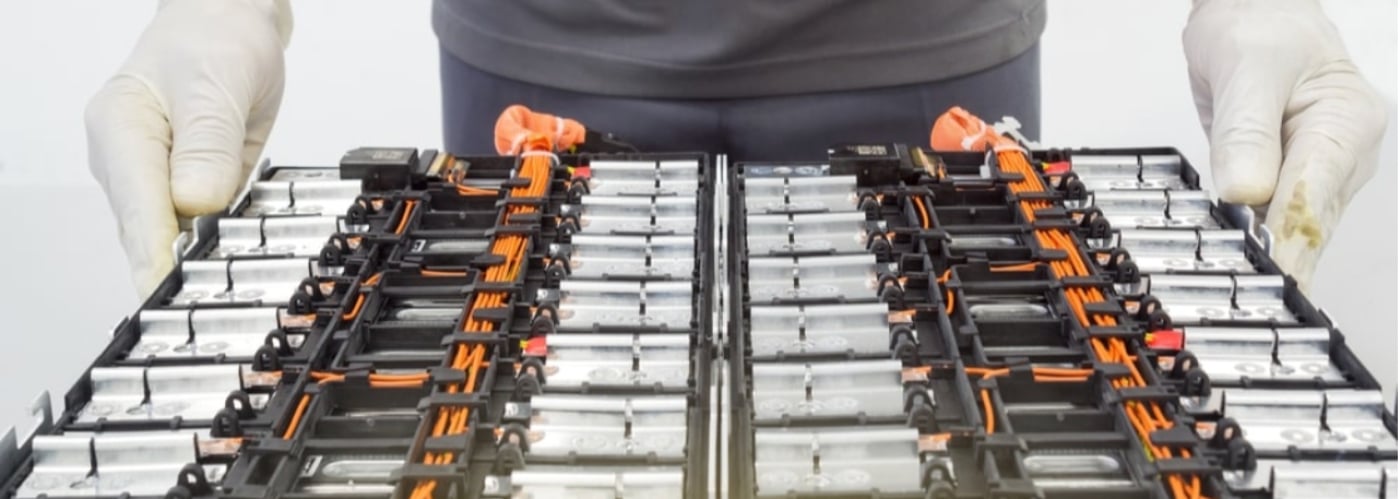 Technician in gloves handling a battery pack, emphasizing electrical components and safety.