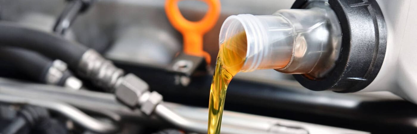Pouring motor oil into a car engine, highlighting vehicle maintenance.